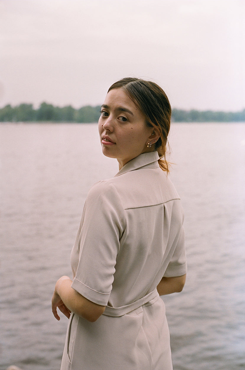 Model standing up,looking back to the camera, Eggnog coloured jumpsuit, brazilian crepe patou, lake, river in the background