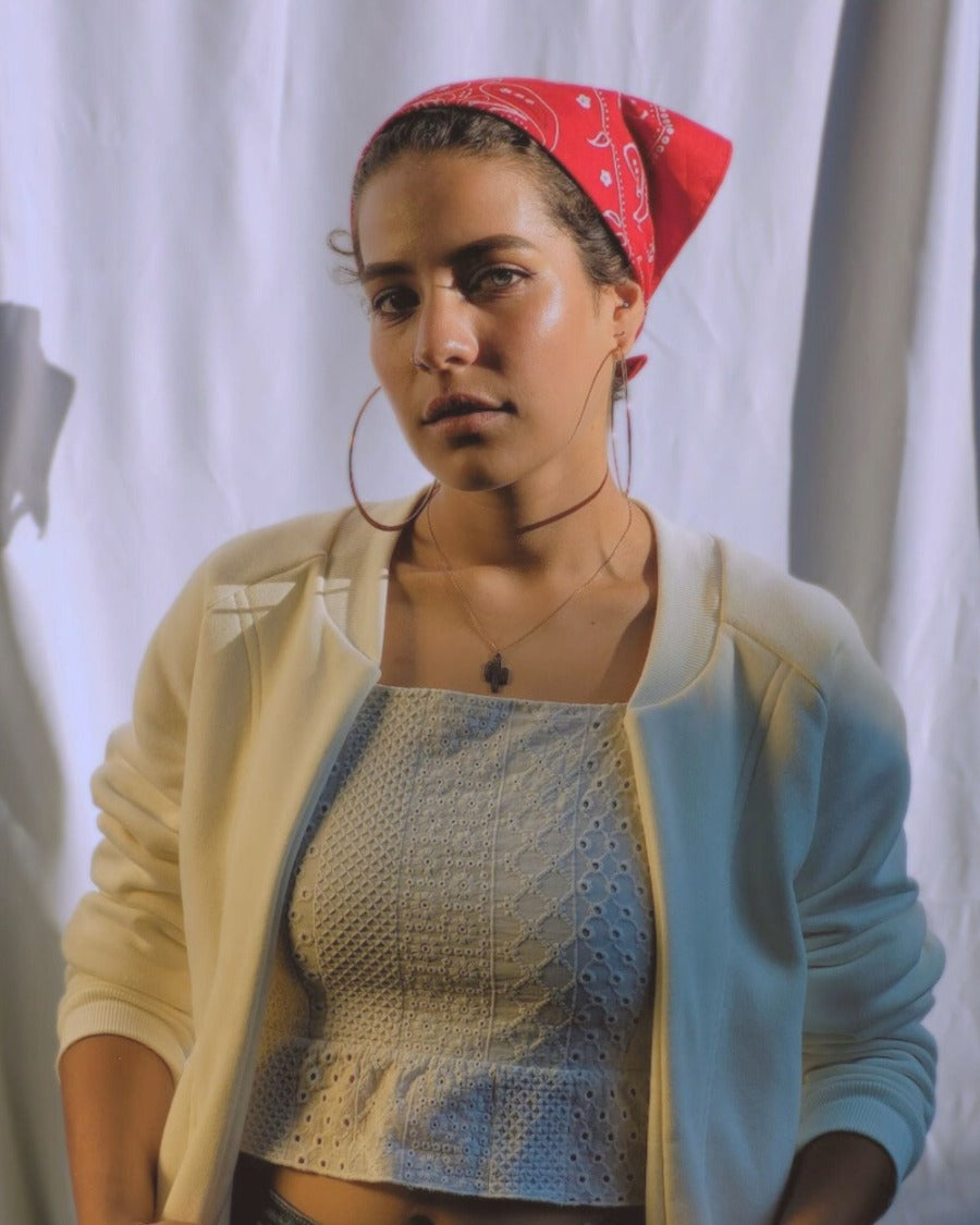 Model looking at the camera on sunny day, white background, crouchet top, golden earrings, red bandana on the head, beije cottom fleece jacket